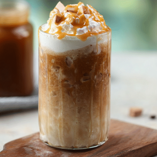 Tall glass of iced coffee with milk, layered and topped with ice cubes.