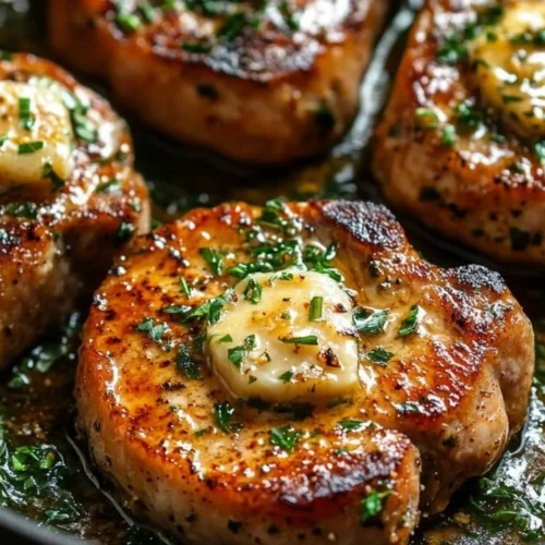 Juicy garlic butter pan-seared pork chops served with herbs.