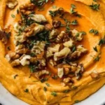 Delicious Pumpkin Whipped Feta Dip served in a bowl with herbs and crackers.
