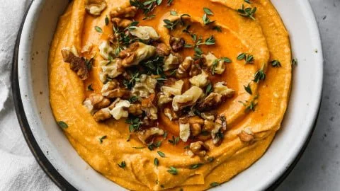 Delicious Pumpkin Whipped Feta Dip served in a bowl with herbs and crackers.
