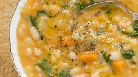 A bowl of the best white bean soup garnished with herbs and spices.