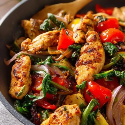 Mediterranean chicken stir fry with grilled chicken strips, vegetables and rice in a black bowl
